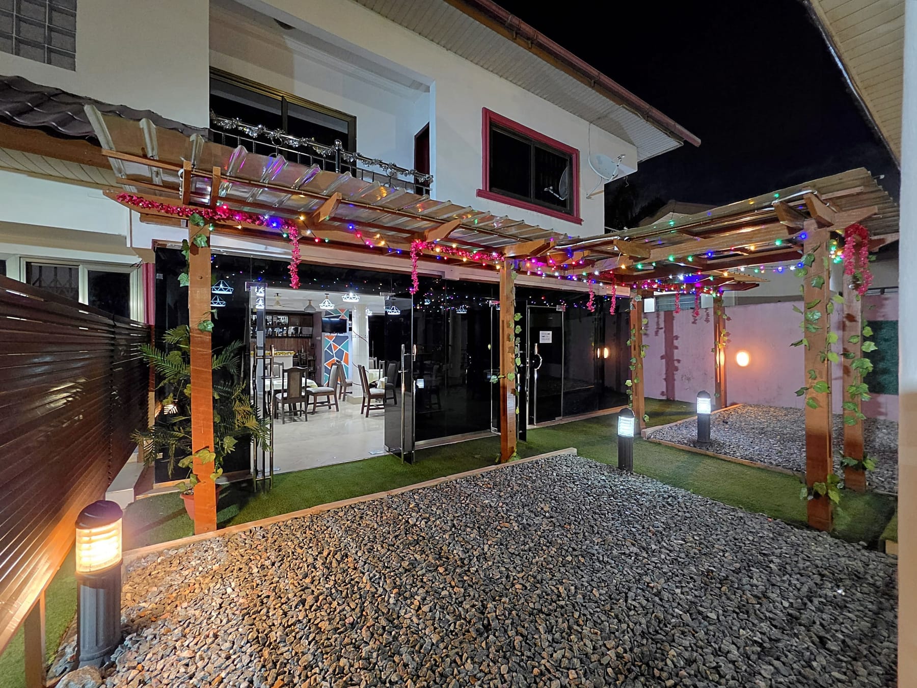 The pergola with its coloured lights at night, at the door of the restaurant